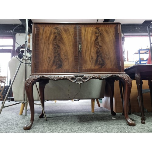 453 - A good quality reproduction drinks cabinate, featuring double flamed mahogany doors revealing a divi... 