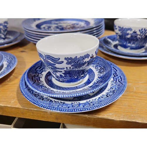 66 - A partial willow pattern dinner set to include 6x trios, 6x dinner plates and 6x bowls all in good o... 