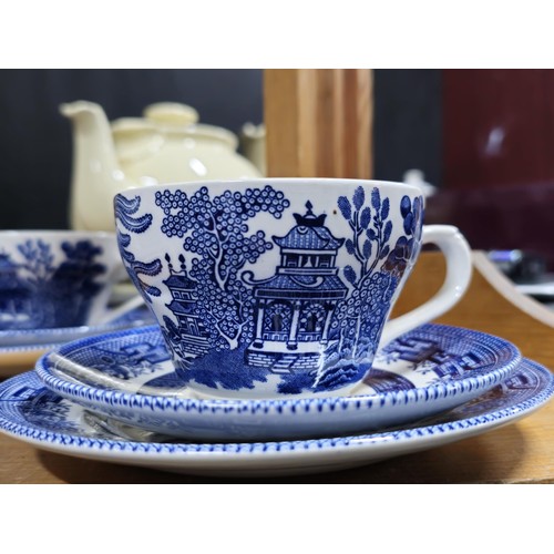 66 - A partial willow pattern dinner set to include 6x trios, 6x dinner plates and 6x bowls all in good o... 