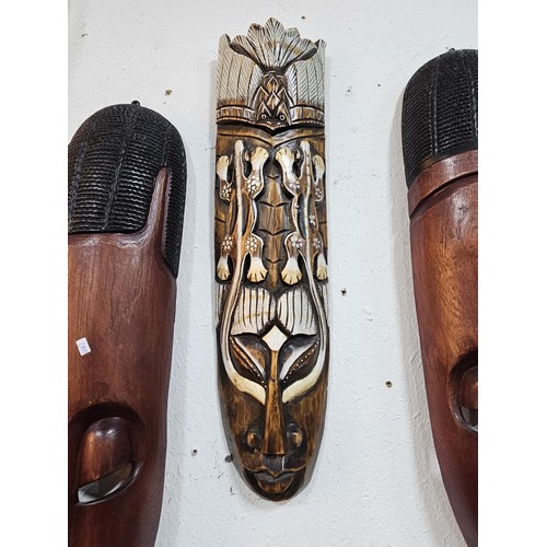 176 - A collection of 4 wall hanging original wooden ethnic face masks, 1 is in striking red, blue and yel... 