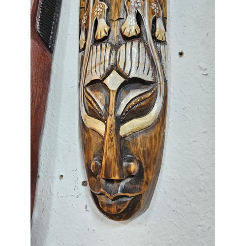 176 - A collection of 4 wall hanging original wooden ethnic face masks, 1 is in striking red, blue and yel... 