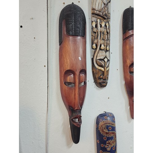 176 - A collection of 4 wall hanging original wooden ethnic face masks, 1 is in striking red, blue and yel... 