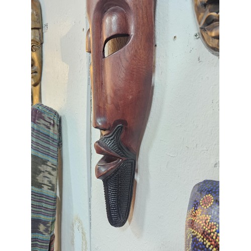 176 - A collection of 4 wall hanging original wooden ethnic face masks, 1 is in striking red, blue and yel... 