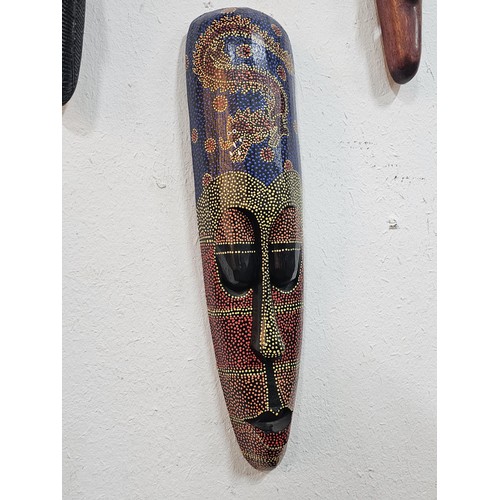 176 - A collection of 4 wall hanging original wooden ethnic face masks, 1 is in striking red, blue and yel... 