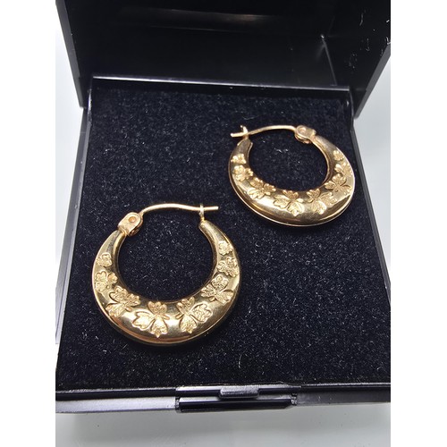 390 - A pair of pretty 9ct yellow gold half hoop earrings having an engraved design with maple leaves, the... 