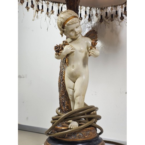 105 - A vintage resin figural lamp with a cherub to the base and an original vintage lampshade decorated w... 