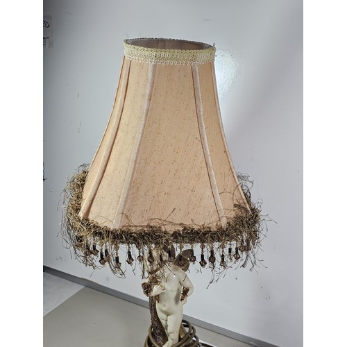 105 - A vintage resin figural lamp with a cherub to the base and an original vintage lampshade decorated w... 