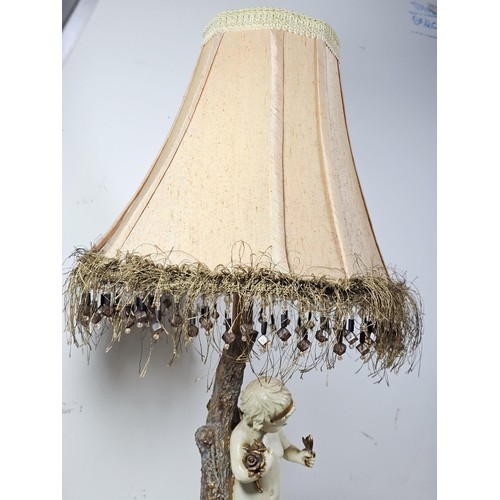 105 - A vintage resin figural lamp with a cherub to the base and an original vintage lampshade decorated w... 