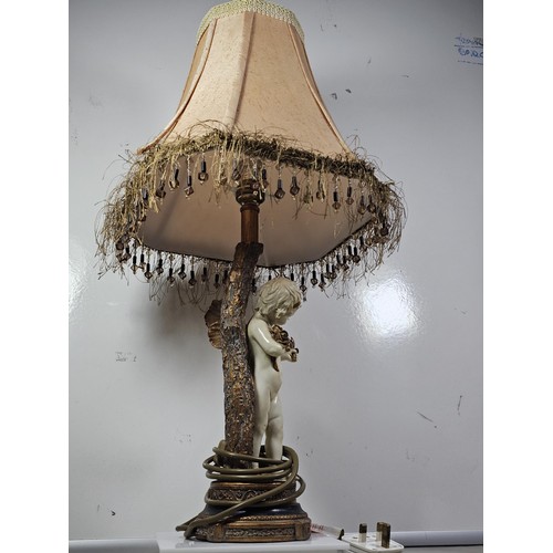 105 - A vintage resin figural lamp with a cherub to the base and an original vintage lampshade decorated w... 