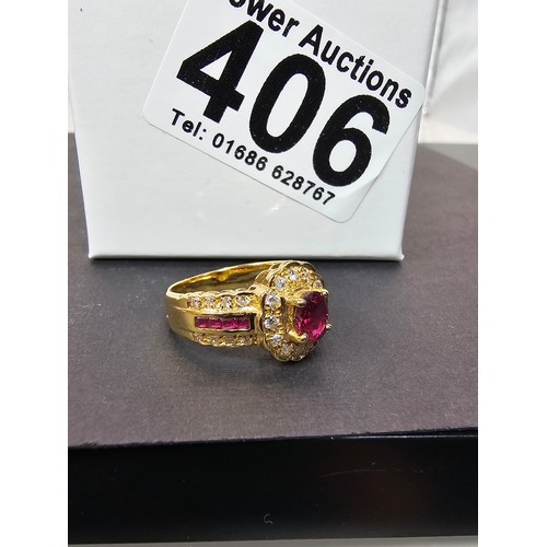 406 - A fine quality 18ct Gold Ruby & Diamond Halo Ring. Claw set with an oval cut natural Ruby weighing 0... 