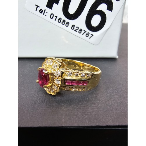406 - A fine quality 18ct Gold Ruby & Diamond Halo Ring. Claw set with an oval cut natural Ruby weighing 0... 