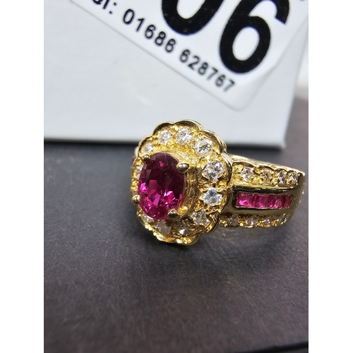 406 - A fine quality 18ct Gold Ruby & Diamond Halo Ring. Claw set with an oval cut natural Ruby weighing 0... 