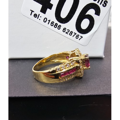 406 - A fine quality 18ct Gold Ruby & Diamond Halo Ring. Claw set with an oval cut natural Ruby weighing 0... 