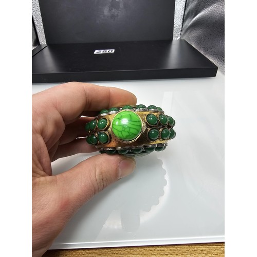 280 - An attractive ornate Asian scent bottle set with green stones having a green stone to the lid, the l... 