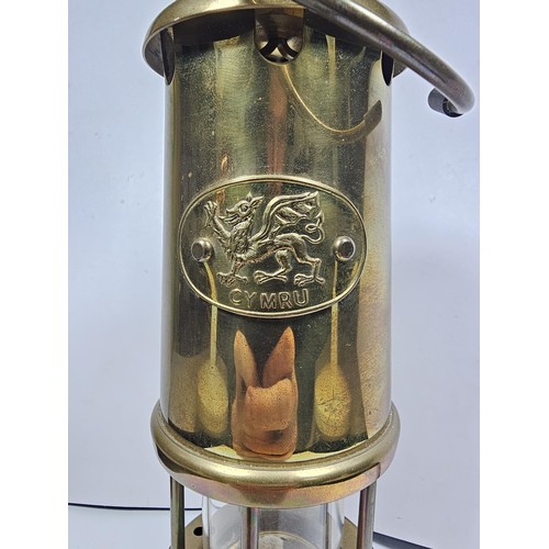 436 - A Welsh brass minors paraffin lamp of cylindrical form applied with a Cymru dragon badge and fully s... 