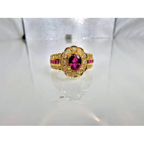 406 - A fine quality 18ct Gold Ruby & Diamond Halo Ring. Claw set with an oval cut natural Ruby weighing 0... 