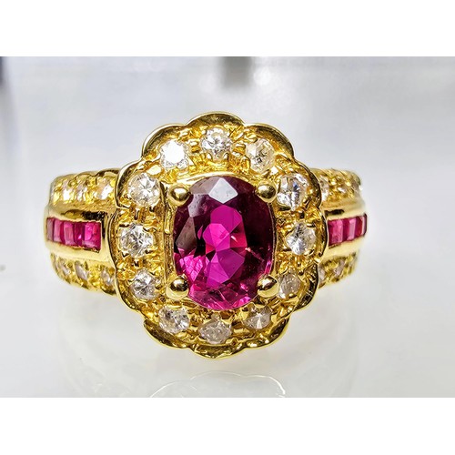 406 - A fine quality 18ct Gold Ruby & Diamond Halo Ring. Claw set with an oval cut natural Ruby weighing 0... 