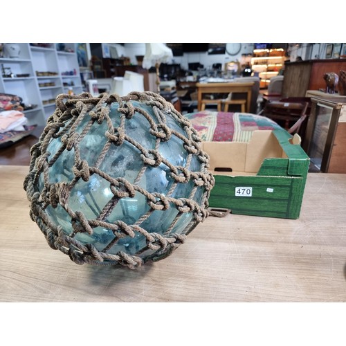 94 - Antique glass hand blown fishing float buoy in good order with original netting surround, the buoy m... 