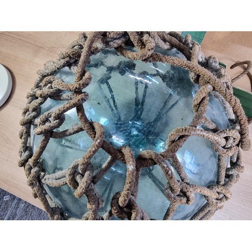 94 - Antique glass hand blown fishing float buoy in good order with original netting surround, the buoy m... 