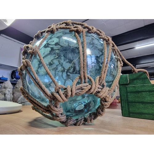 94 - Antique glass hand blown fishing float buoy in good order with original netting surround, the buoy m... 