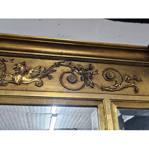 54 - A large ornate gilded triple over mantle bevel edged mirror with a Egyptian frieze to the top, a pha... 