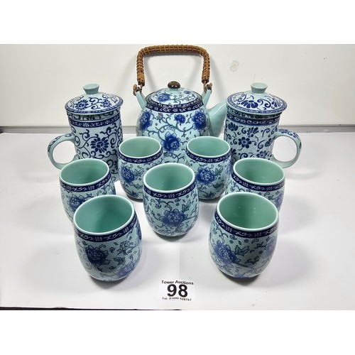 98 - A oriental tea set with a blue floral pattern complete with a teapot with a bamboo handle. Teapot is... 