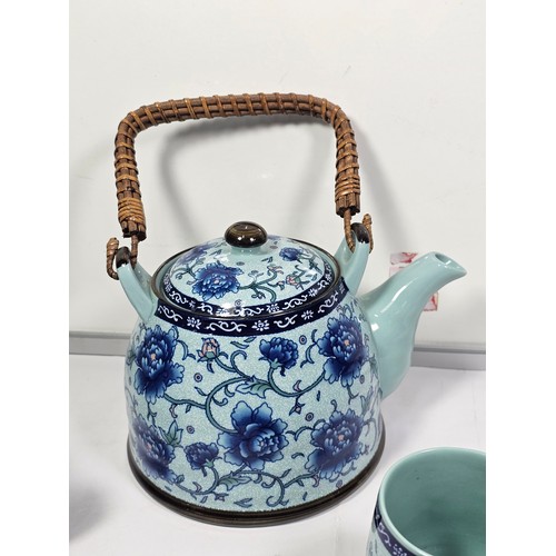98 - A oriental tea set with a blue floral pattern complete with a teapot with a bamboo handle. Teapot is... 