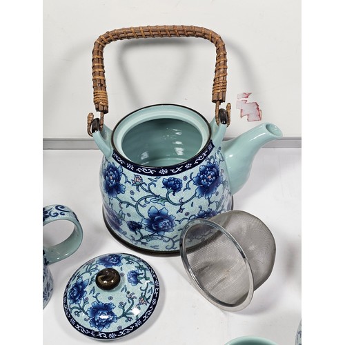 98 - A oriental tea set with a blue floral pattern complete with a teapot with a bamboo handle. Teapot is... 