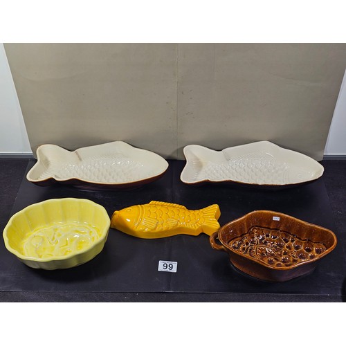 99 - A collection of 5 jelly moulds in earthenware to include 3 fish design moulds, a brown glaze mould a... 