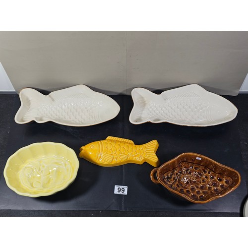 99 - A collection of 5 jelly moulds in earthenware to include 3 fish design moulds, a brown glaze mould a... 