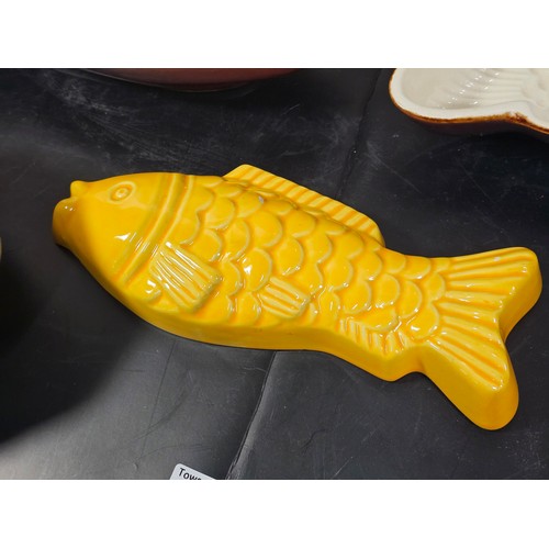 99 - A collection of 5 jelly moulds in earthenware to include 3 fish design moulds, a brown glaze mould a... 