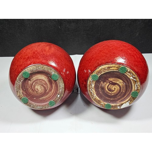 111 - A pair of red bulbous vases both are studio pottery pieces with a mottled design. Both in good order... 