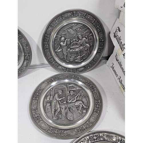 116 - A collection of 8x tin plates each with a different trade design to the front to include Glassblower... 