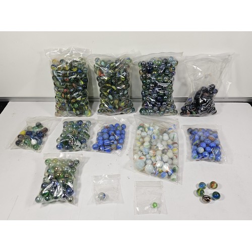 144 - A box containing 8 bags of assorted marbles to include traditional rainbow glass marbles, white marb... 
