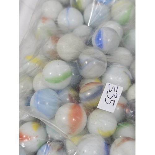 144 - A box containing 8 bags of assorted marbles to include traditional rainbow glass marbles, white marb... 