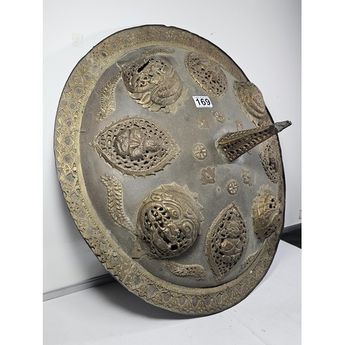 169 - An antique early 20th century Indo-Persian metal Dhal shield with grip bar, the shield is decorated ... 