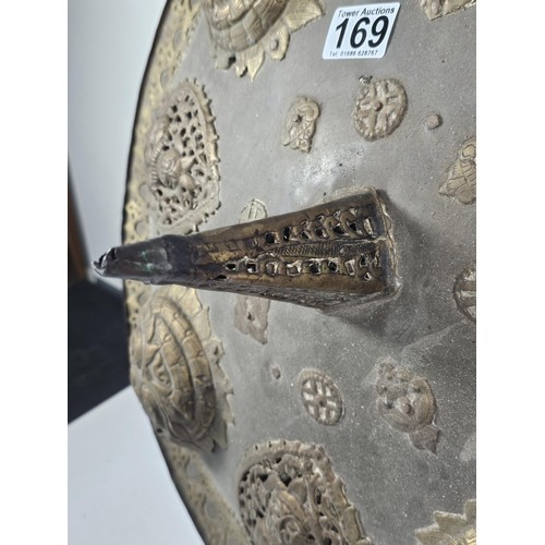 169 - An antique early 20th century Indo-Persian metal Dhal shield with grip bar, the shield is decorated ... 