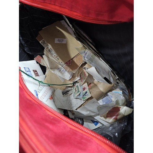 202 - A red hold bag containing a very large quantity of assorted loose stamps to include British stamps, ... 