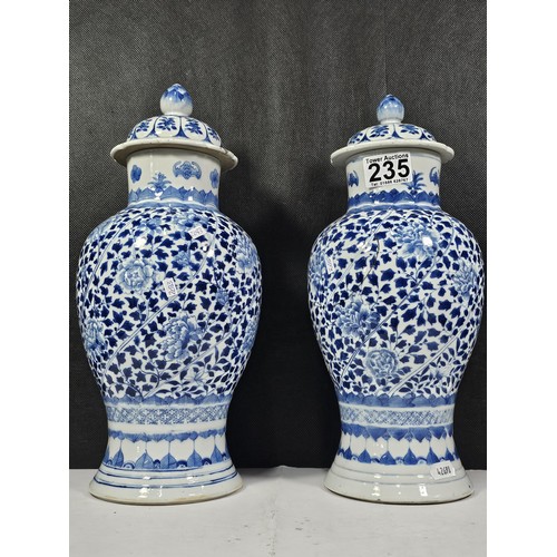 235 - A pair of Chinese blue and white lidded vases decorated with dense floral patterns in under glazed c... 