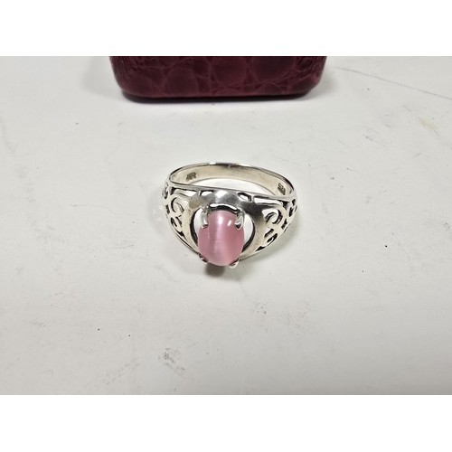 203 - An attractive 925 silver ring, having pierced shoulders, set with an attractive pink cats eye type c... 