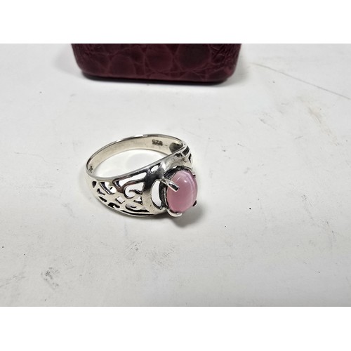 203 - An attractive 925 silver ring, having pierced shoulders, set with an attractive pink cats eye type c... 