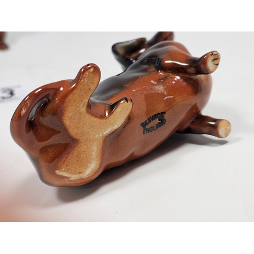 183 - A collection of 3 Beswick ceramic dachshund figurines, each modelled in characteristic poses with a ... 