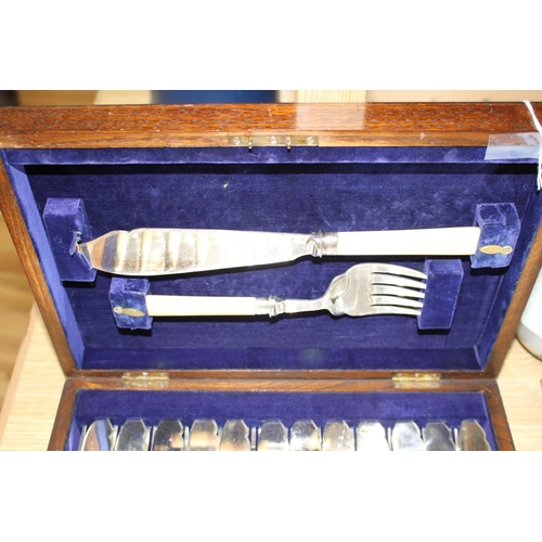 140 - A cased set of twelve pairs of plated fish knives and forks with servers, silver banded ivorine hand... 