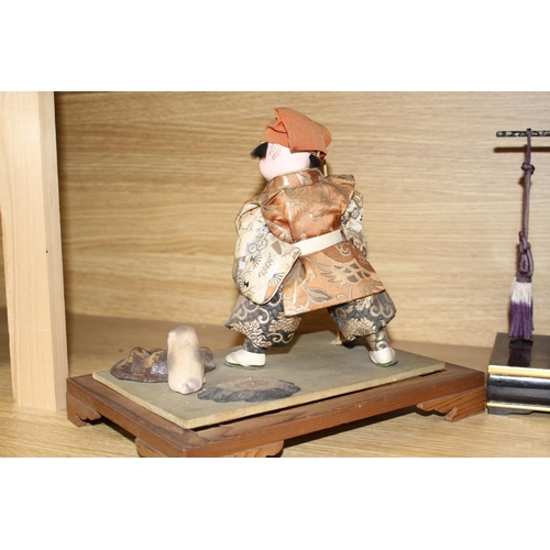 144 - A Japanese late Meiji period composition and fabric figure of a boy farmer holding an adze with pupp... 