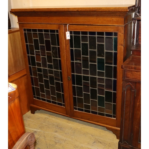 1070 - An Edwardian oak bookcase enclosed by stained leaded glass doors, W124cm, D.34cm, H.128cm