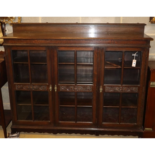 1098 - A 1920's carved oak three door bookcase, W.152cm, D.36cm, H.120cm