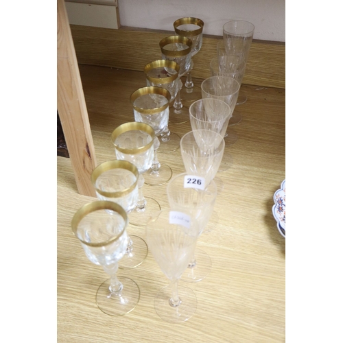 1226 - A set of seven gilt rimmed wine glasses and eight glass flutes