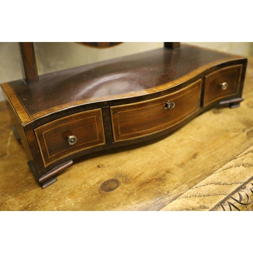 31 - A shield-shaped swing frame mahogany toilet mirror, cross-banded and line-inlaid, the serpentine-fro... 