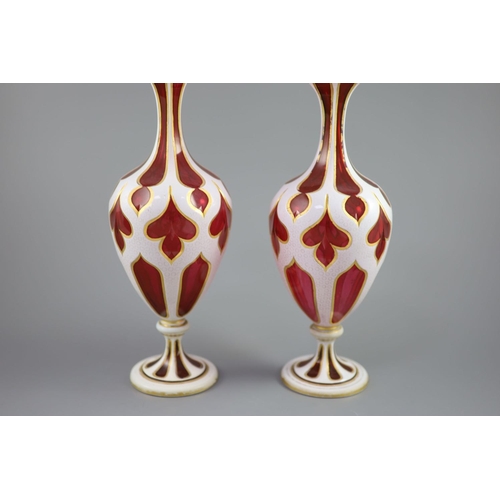 103 - A pair of Bohemian white and ruby overlaid glass vases, the shaped panel cuts with gilded edges, the... 