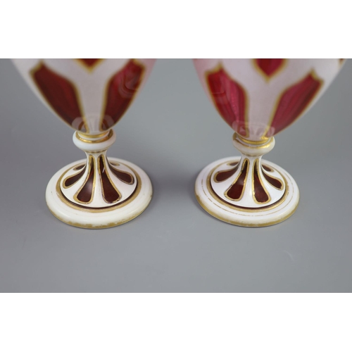 103 - A pair of Bohemian white and ruby overlaid glass vases, the shaped panel cuts with gilded edges, the... 